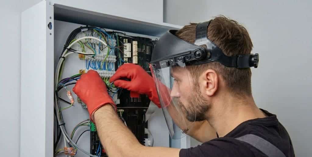 Technicien réalisant une maintenance tout en étant équipé de ses EPI